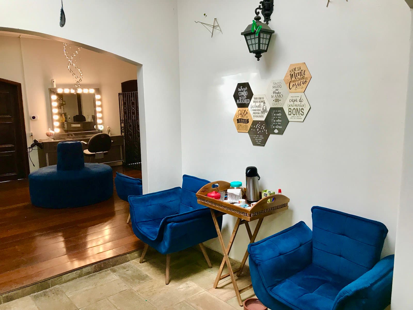 Sala de espera com poltronas azuis e a bancada de espelho ao fundo